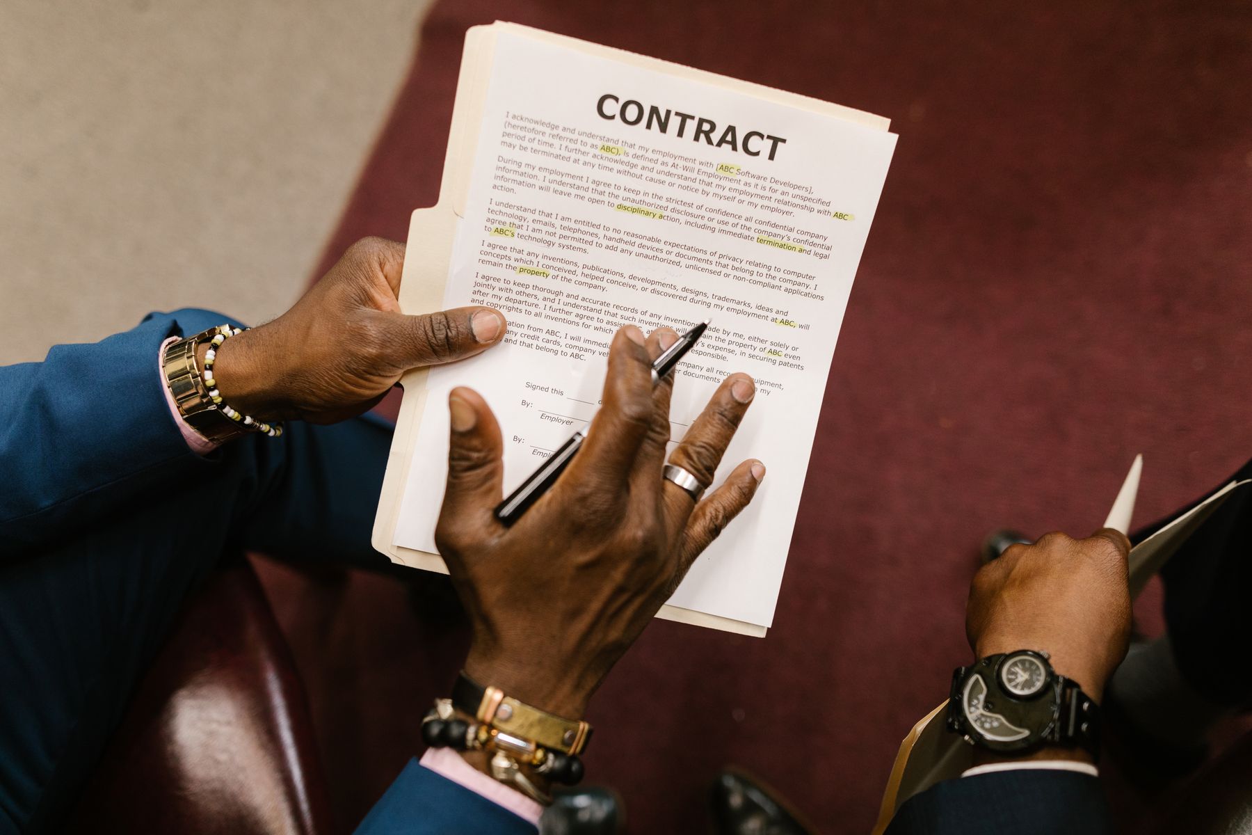 Close-up of hands holding a printed contract and pen during a seated discussion.